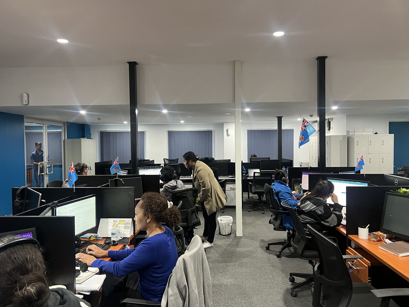 PCS Suva office floor with Fiji flag and agents working at workstations